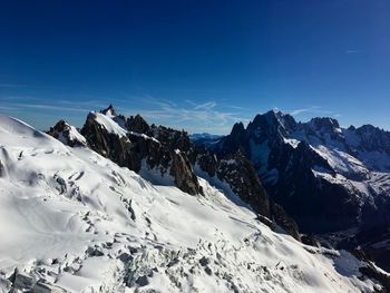 Scenic view of snow covered mountains against blue sky