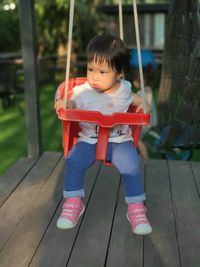Cute baby girl sitting on swing at playground