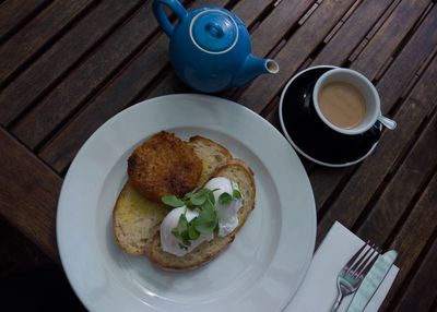 High angle view of breakfast served in plate by tea cup on wooden table