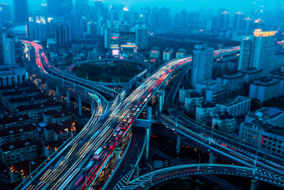 High angle view of light trails on road amidst buildings in city