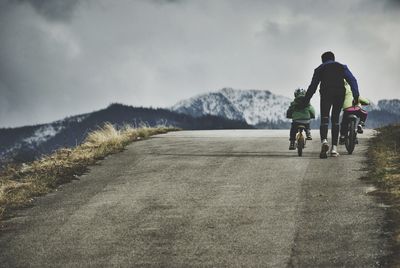 Men riding motorcycle on road against sky