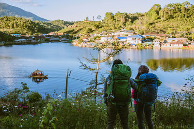 Rear view of couple standing by lake during winter