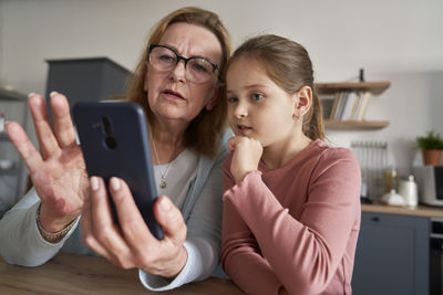 Grandmother and granddaughter talking on video call at home