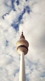 Low angle view of communications tower against cloudy sky