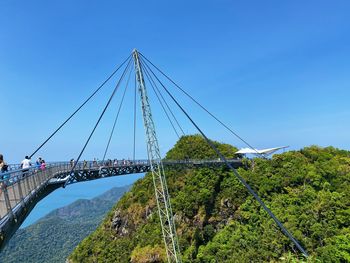 Low angle view of suspension bridge against clear blue sky