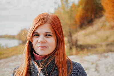 Portrait of happy young red haired woman smiling and looking aside. local travel. 