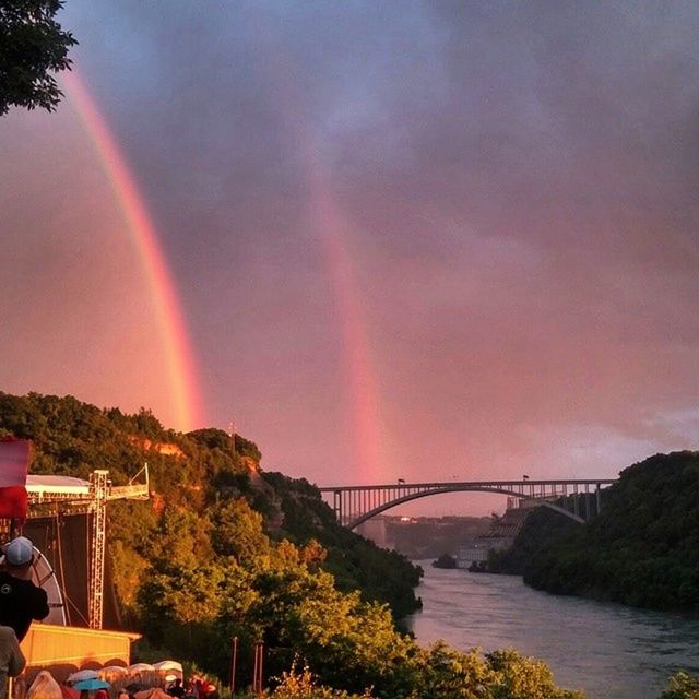 connection, bridge - man made structure, rainbow, sky, water, tree, built structure, architecture, river, scenics, beauty in nature, cloud - sky, bridge, nature, sunset, multi colored, transportation, tranquil scene, tranquility, suspension bridge