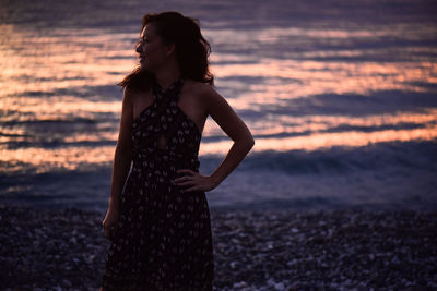 Full length of woman standing by sea during sunset