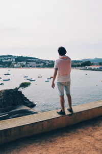 Rear view of man looking at sea against sky