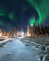 Snow covered landscape against dramatic sky at night