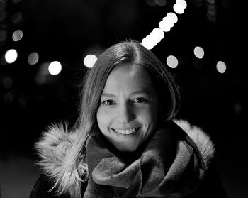 Portrait of smiling young woman outdoors at night