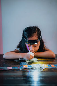 Portrait of young woman wearing sunglasses while sitting on table