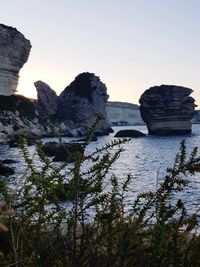 Rock formation in sea against clear sky