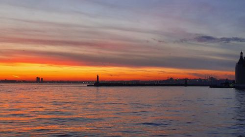 Scenic view of sea against dramatic sky during sunset