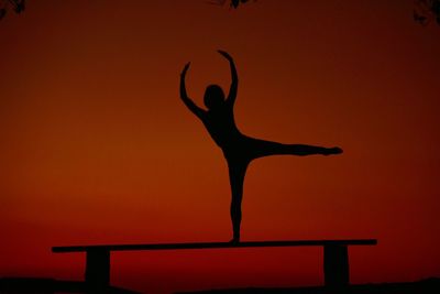 Silhouette woman with arms outstretched against sky during sunset