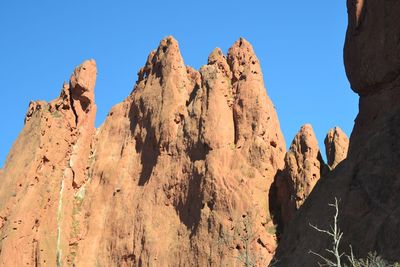 Low angle view of rocks against clear blue sky