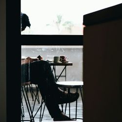 Silhouette man standing by window against sky