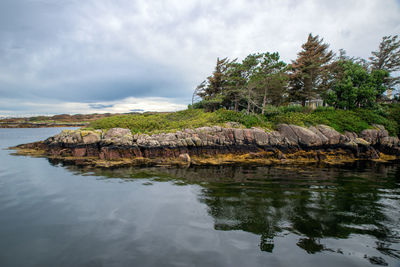 Scenic view of rocks by sea against sky