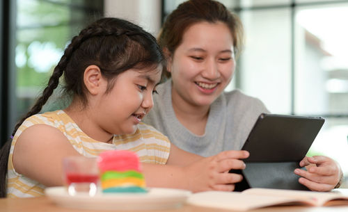 Young woman using mobile phone while sitting on table