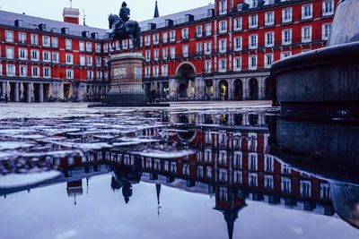 Reflection of building in puddle on canal in city