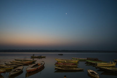 Boats moored in sea against clear sky at dusk
