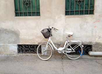 Bicycle leaning on wall by street