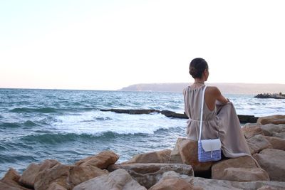 Rear view of man standing on beach against clear sky