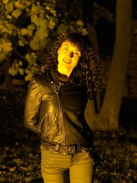 Portrait of smiling young woman standing in park at night