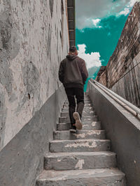 Rear view of man walking on staircase