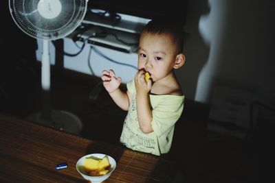 Girl eating food on table at home