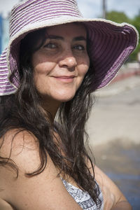 Woman wearing a big pink hat looking to the side. she has green eyes. 