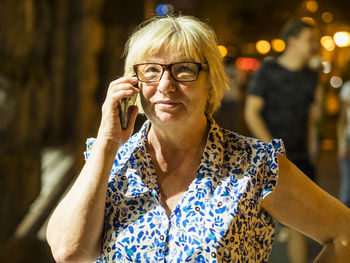 Light falling on senior woman talking on mobile phone at night