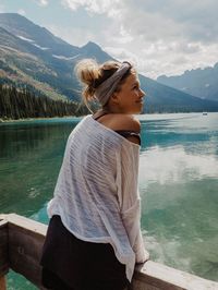 Woman standing at observation point by lake against mountains