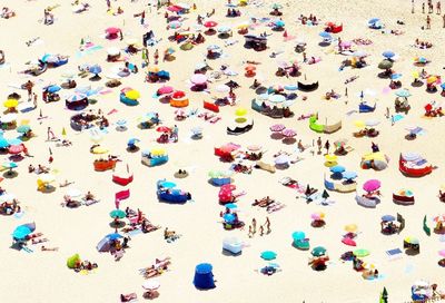 High angle view of people and parasols at beach during sunny day