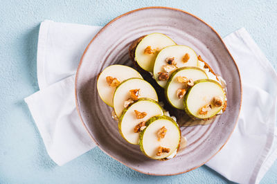 Close up of sandwiches on rye bread with arugula, pear, honey and nuts on a plate top view