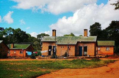 Houses on field against cloudy sky