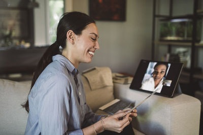 Smiling female entrepreneur with fabric swatch talking through laptop on video conference while working at home