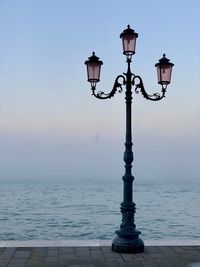 Street light by sea against sky