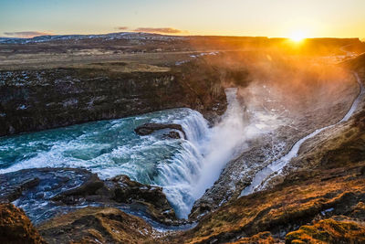 Scenic view of waterfall against sky during sunset