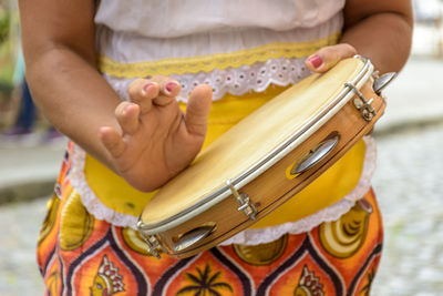 Young woman in colorful clothes playing the tambourine during a samba performance in salvador