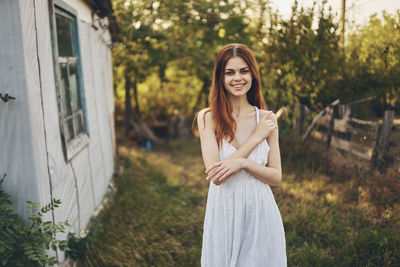 Portrait of smiling young woman standing against plants