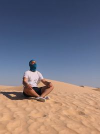 Man on sand dune in desert against clear sky