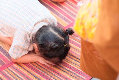 High angle view of girl praying on mat