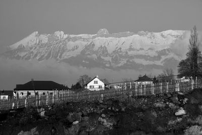 Houses and snowcapped mountains against sky