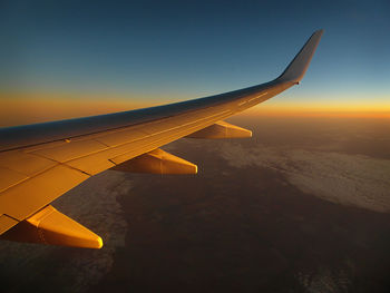 Airplane flying in sky at sunset