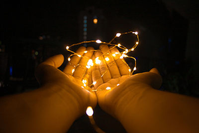 Close-up of hand holding illuminated lights at night