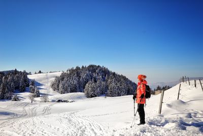 Man standing on snow covered landscape against blue sky