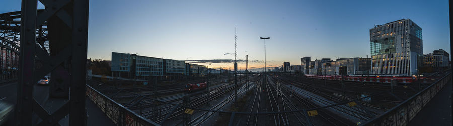 Railroad tracks amidst buildings in city against sky during sunset