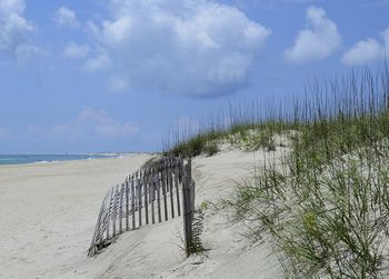 Wooden posts on beach against sky