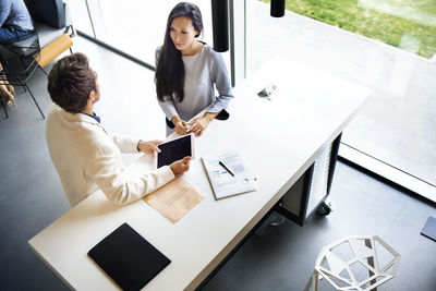 High angle view of business people discussing while standing by desk